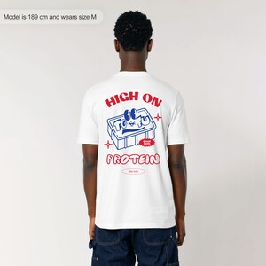 May include: White t-shirt with a blue and red graphic of a tofu block with the text "HIGH ON TOFU Great Taste PROTEIN Rat tofu" printed on the back.