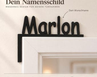 May include: A black, L-shaped name sign featuring the name Marlon in a rounded, sans-serif font. The sign is designed to sit on the corner of a door frame. The text on the image includes 'Dein Namensschild', 'Marlon', and 'Dein Wunschname'.