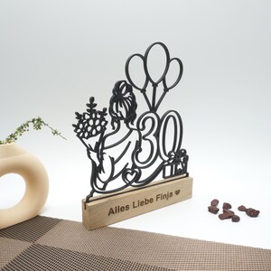 Line-Art-Aufsteller zum Geburtstag mit Gravur „Alles Liebe Finja“ neben Vase und Deko.