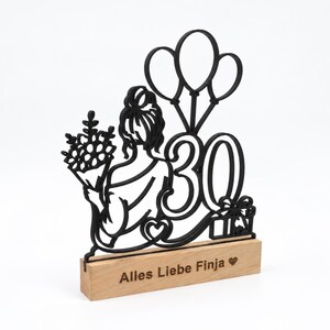 Schwarzer Line-Art-Aufsteller mit Frau, Ballons und Zahl 30 auf Holzsockel, Ansicht von der Seite.