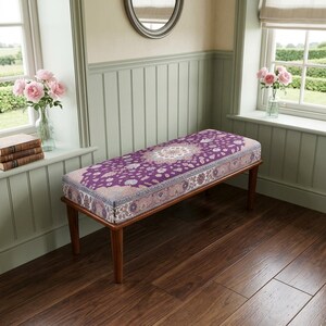 a wooden bench with a purple and white patterned cushion, placed in a room with a wooden floor and a window with pink roses.
