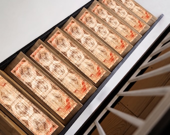 May include: A set of eight stair treads featuring a patterned design. The treads are made of wood and have a light brown finish. The pattern is a geometric design with red and white accents.