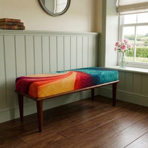 May include: A rectangular bench with four tapered dark wood legs and a cushioned seat featuring a vibrant, swirling pattern of red, orange, yellow and teal colours. The upholstery has a textured, woven appearance with a dense, intricate design.
