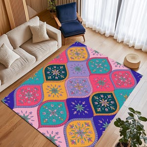 Puede incluir: Una colorida alfombra con un patrón geométrico de diseños florales estilizados en tonos de rosa, turquesa, amarillo, morado y azul. La alfombra rectangular está colocada sobre un suelo de madera, añadiendo un toque vibrante a la decoración de la habitación.