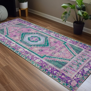 May include: A long, rectangular rug with a pink, green, and purple geometric pattern. The rug has a traditional Persian design with intricate details.