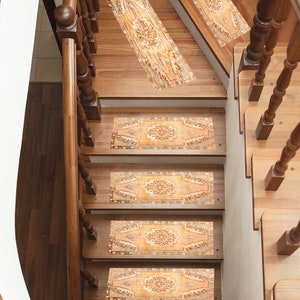 May include: A set of five beige and brown patterned stair treads with a floral design. The treads are placed on a wooden staircase with a wooden handrail.