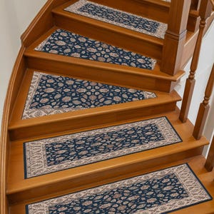 Può includere: Set di tappeti per scale con un motivo floreale blu navy e beige. I tappeti, di forma rettangolare, sono posizionati su scale in legno. Aggiungono un elemento decorativo alla scala.