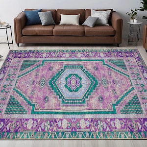 May include: A colorful rug with a geometric pattern in shades of pink, purple, green, and white. The rug has a distressed look and a fringed edge.