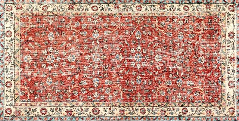 May include: A vintage red rug with a floral pattern. The rug has a cream-colored border with a blue and cream floral design.