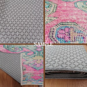 Puede incluir: Primer plano de una alfombra gris con un patr&oacute;n de diamantes. La alfombra est&aacute; doblada por la mitad y los bordes son visibles. La alfombra est&aacute; sobre una superficie de madera. La palabra "SAMPLE" est&aacute; impresa en blanco sobre un fondo marr&oacute;n.