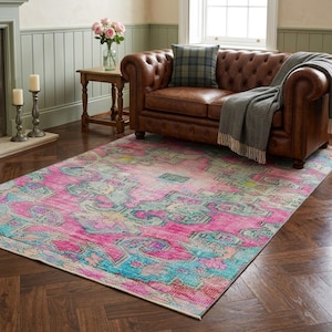 May include: A rectangular area rug featuring a distressed, faded pattern in vibrant shades of hot pink, turquoise, and muted yellow. The rug displays an intricate, symmetrical medallion design with ornate borders, covering the floor space.