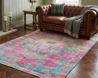 May include: A rectangular area rug featuring a distressed, faded pattern in vibrant shades of hot pink, turquoise, and muted yellow. The rug displays an intricate, symmetrical medallion design with ornate borders, covering the floor space.