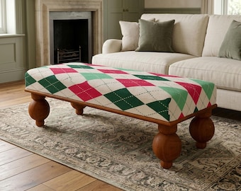 Può includere: Un pouf rettangolare con una superficie in tessuto color crema caratterizzata da un motivo a rombi ripetuto nelle tonalità del verde scuro, verde chiaro e rosso. Il mobile è sostenuto da quattro gambe in legno scuro a forma di sfera.