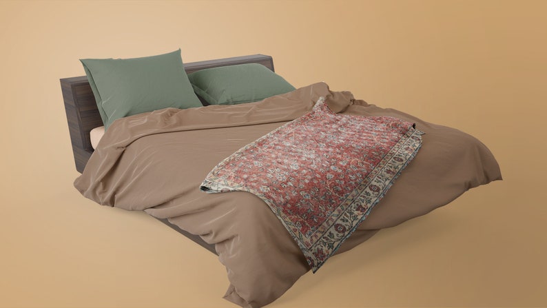 May include: A brown bed with a green pillow and a red and white patterned throw blanket.