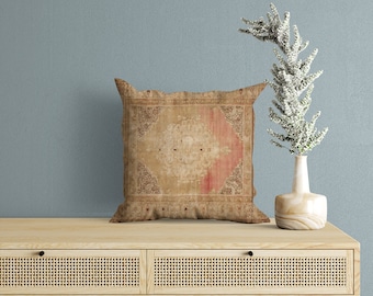May include: A decorative throw pillow with a vintage rug pattern in shades of brown, beige, and red. The pillow is sitting on a light wood dresser with two drawers.