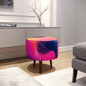 Könnte beinhalten: Ein runder Hocker mit einem lebendigen Farbverlauf in Pink, Orange und Dunkelblau, verziert mit feinen weißen topografischen Linienmustern. Das Möbelstück steht auf drei konisch geformten Holzbeinen, die für einen stabilen Stand sorgen.
