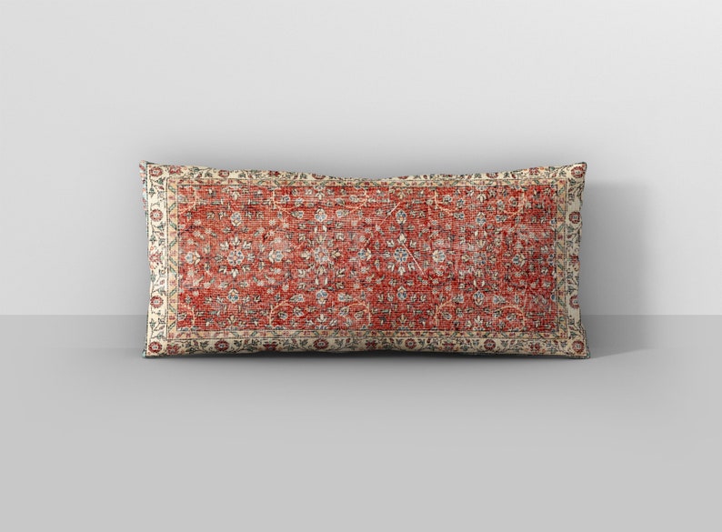 May include: A rectangular cushion with a red, white and blue floral pattern. The cushion has a cream-coloured border with a floral design.