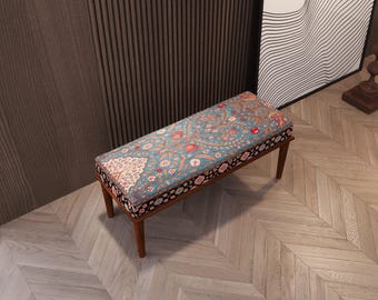 May include: A rectangular bench with a floral patterned cushion in teal, red, and cream. The cushion is bordered with a black and floral design. The bench has four wooden legs.