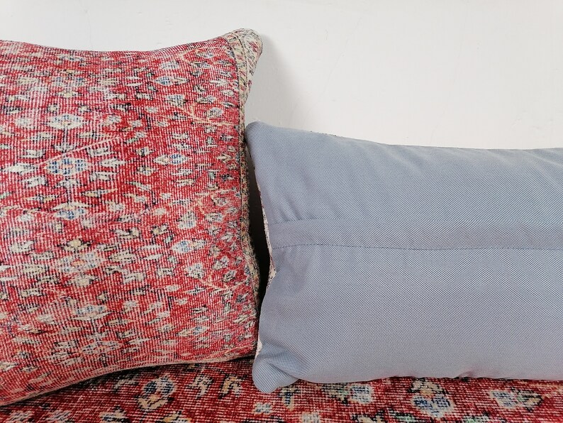 May include: Two decorative throw pillows, one with a red and white patterned fabric and the other with a solid light blue fabric.