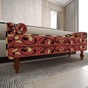 a red and black patterned bench with a floral design, placed on a gray rug in a room with a window and curtains.