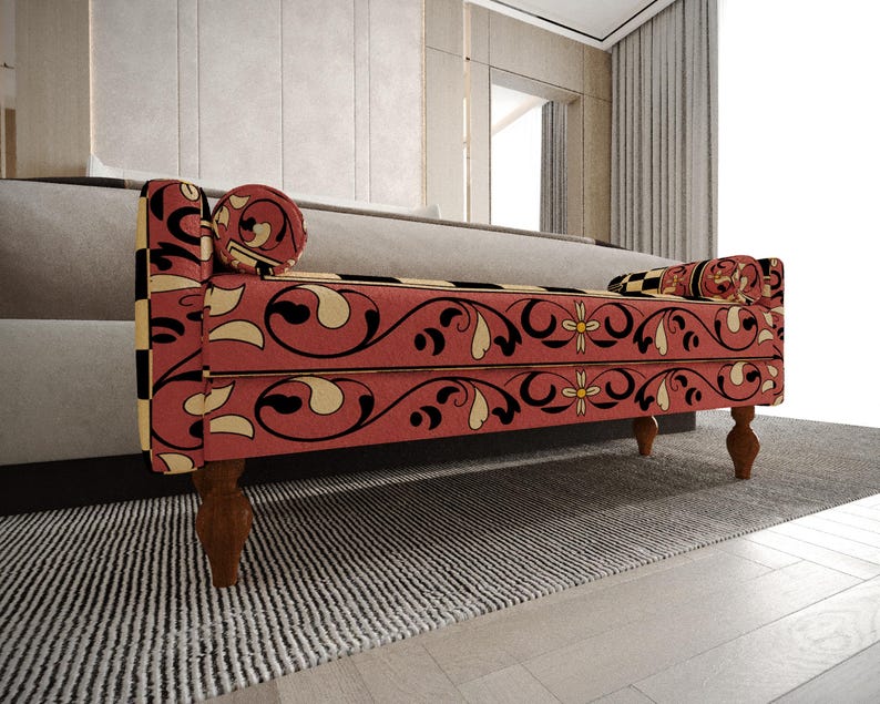a red and black patterned bench with a floral design, placed on a gray rug in a room with a window and curtains.
