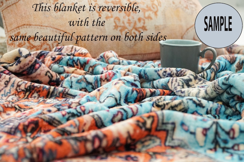 K&ouml;nnte beinhalten: Eine blaue und orangefarbene Fleece-Decke mit dem Text "This blanket is reversible, with the same beautiful pattern on both sides" und "SAMPLE" auf dem Bild.