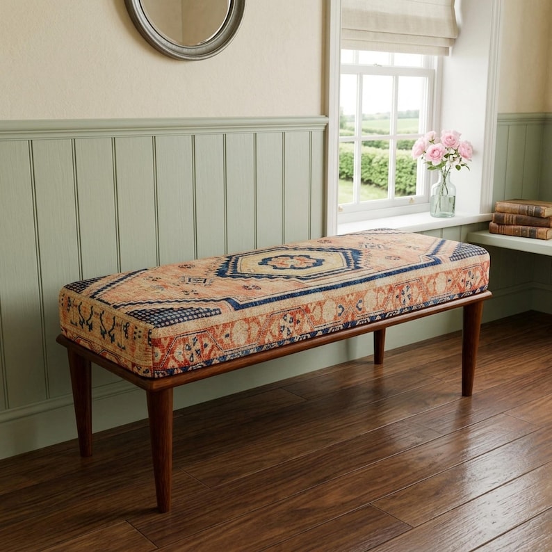 a wooden bench with a colorful patterned cushion, placed in a room with a window and a bookshelf.