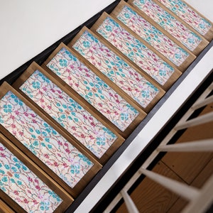 May include: A set of wooden stair treads with a patterned fabric inlay. The fabric is a white background with pink and blue floral designs.
