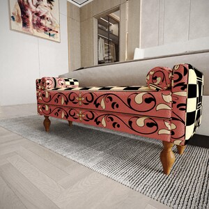 a modern, colorful bench with a floral pattern on the upholstery, placed on a gray rug in a room with a white wall and a painting.