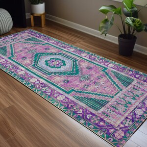 May include: A long, rectangular rug with a pink, green, and purple geometric pattern. The rug has a traditional Persian design with intricate details.