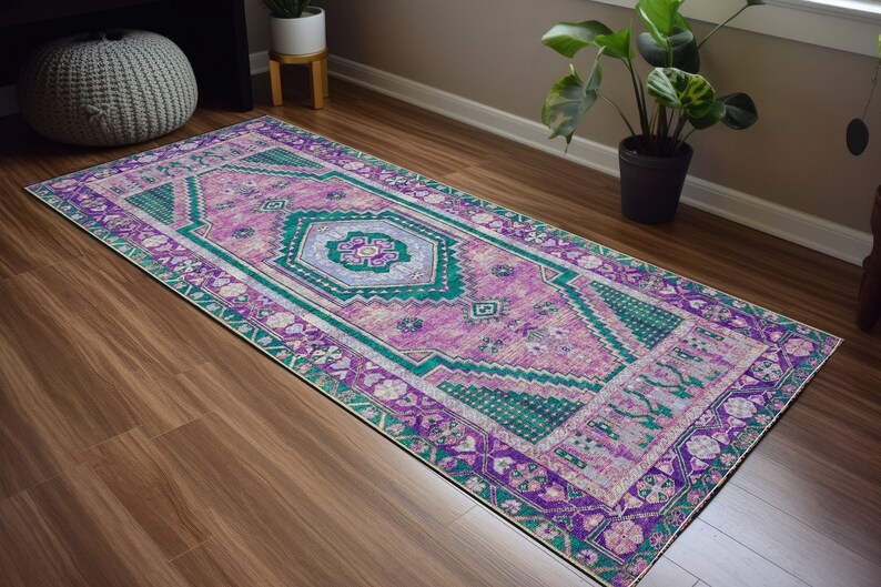 May include: A long, rectangular rug with a pink, green, and purple geometric pattern. The rug has a traditional Persian design with intricate details.