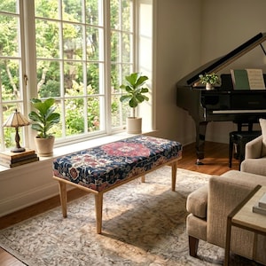 May include: A rectangular upholstered bench featuring a dark blue fabric with a multi-colored floral and geometric pattern in shades of red, cream, and gold. The bench is supported by four light-toned wooden legs with a tapered, cylindrical design.
