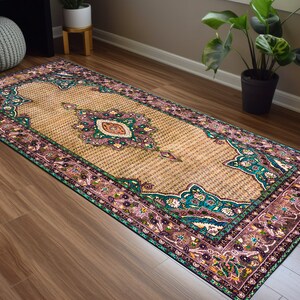 May include: A long, rectangular rug with a beige background and a colorful floral pattern. The rug has a teal, pink, and green border with intricate details.