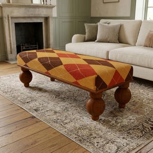 May include: A rectangular ottoman featuring a vibrant argyle pattern in shades of orange, yellow, and brown. The piece is supported by four large, spherical wooden legs, providing a stable base for this functional furniture item.