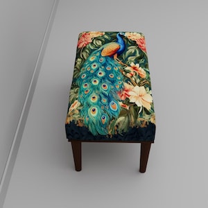 Op de afbeelding: Gestoffeerde bank met een pauwenontwerp. De stof heeft een pauw met een blauwe en groene staart, omringd door bloemen in tinten oranje en crème. De bank heeft donkerbruine houten poten.