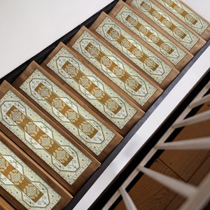 May include: A set of eight stair treads with a patterned design in shades of beige, brown, and blue. The treads are made of wood and have a non-slip surface.