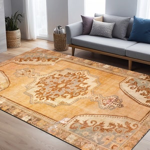 Puede incluir: Una alfombra de estilo vintage con fondo beige y intrincados patrones florales marrones y azules. La alfombra tiene un aspecto descolorido y desgastado, lo que le da un toque &uacute;nico y antiguo.