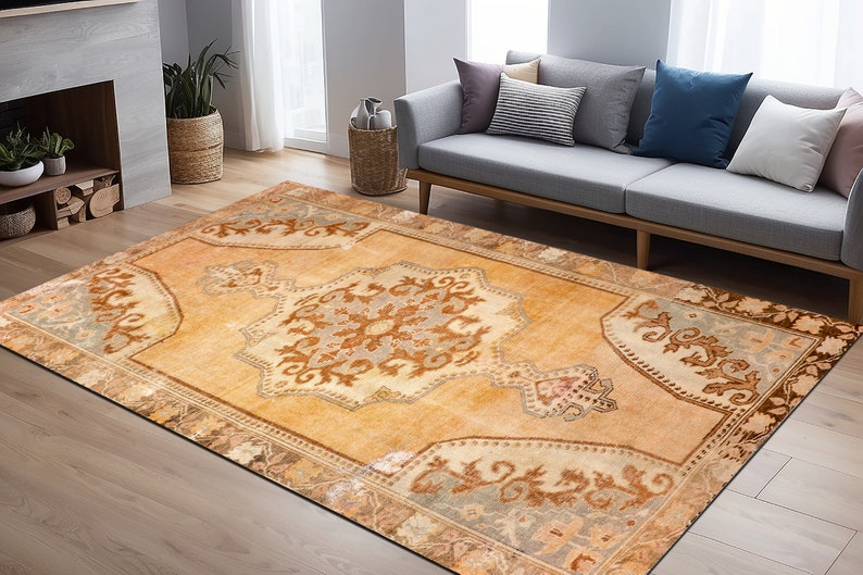 Puede incluir: Una alfombra de estilo vintage con fondo beige y intrincados patrones florales marrones y azules. La alfombra tiene un aspecto descolorido y desgastado, lo que le da un toque &uacute;nico y antiguo.