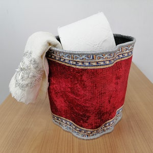 Peut inclure: Un porte-mouchoirs en velours rouge avec une bordure décorative. Le porte-mouchoirs est rempli d'un rouleau de papier toilette blanc et d'un tissu blanc.