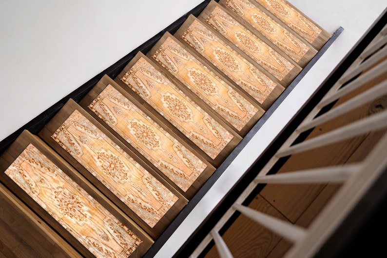 May include: A set of six patterned stair treads in beige and brown tones with a floral design. The treads are made of a soft, durable material and are designed to help prevent slips and falls on stairs.