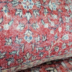 May include: Close-up of a red rug with a floral pattern. The rug has a detailed design with small flowers and leaves in shades of blue, white, and green.