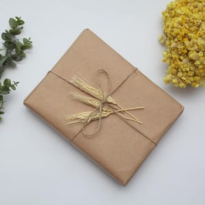 May include: A brown paper gift package tied with twine and decorated with dried wheat stalks.