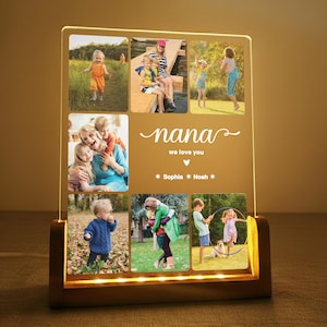 May include: A personalized photo display with a wooden base and a clear acrylic panel. The panel features multiple family photos and the text "nana we love you" with names. The base has warm LED lights.