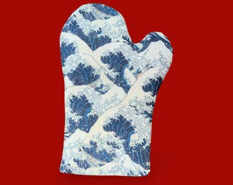 Puede incluir: Un guante de cocina con un diseño de olas azules y blancas, inspirado en la obra japonesa "La Gran Ola de Kanagawa". El guante está diseñado para uso en la cocina y tiene un fondo rojo.