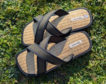 May include: A pair of black and brown sandals with woven straw soles and adjustable straps. The sandals have the word "remarkable" printed on the soles.