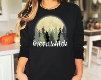 Könnte beinhalten: Schwarzer Pullover mit einem Aufdruck einer Vollmond- und Wald-Silhouette. Der Text "Green Witch" ist unter dem Aufdruck gedruckt.