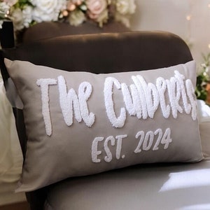 May include: A grey throw pillow with white embroidered text that reads "The Culberts EST. 2024".