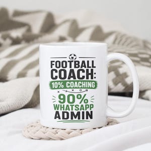 May include: White ceramic mug with the text "FOOTBALL COACH: 10% COACHING 90% WHATSAPP ADMIN" in black and green. The mug has a white handle and sits on a beige coaster. A football graphic is above the text.