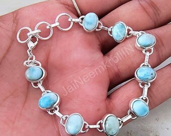May include: A silver chain bracelet with oval-shaped blue and white gemstone beads. The bracelet has a lobster claw clasp.