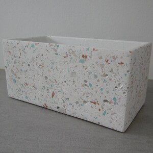 May include: White rectangular planter with a speckled terrazzo finish. The planter has a light grey background with small flecks of red, blue, and brown.
